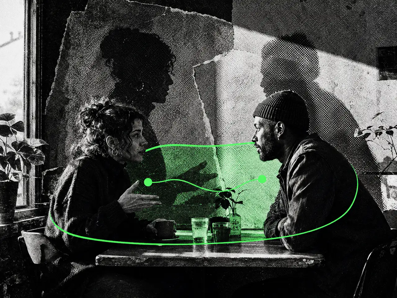 Two adults converse at a cafe table in front of paper silhouettes, with a green line enclosing the space between them.